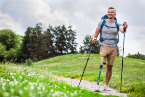 Full length of a nice positive young man with prosthesis having a walk outdoors and enjoying his hobby